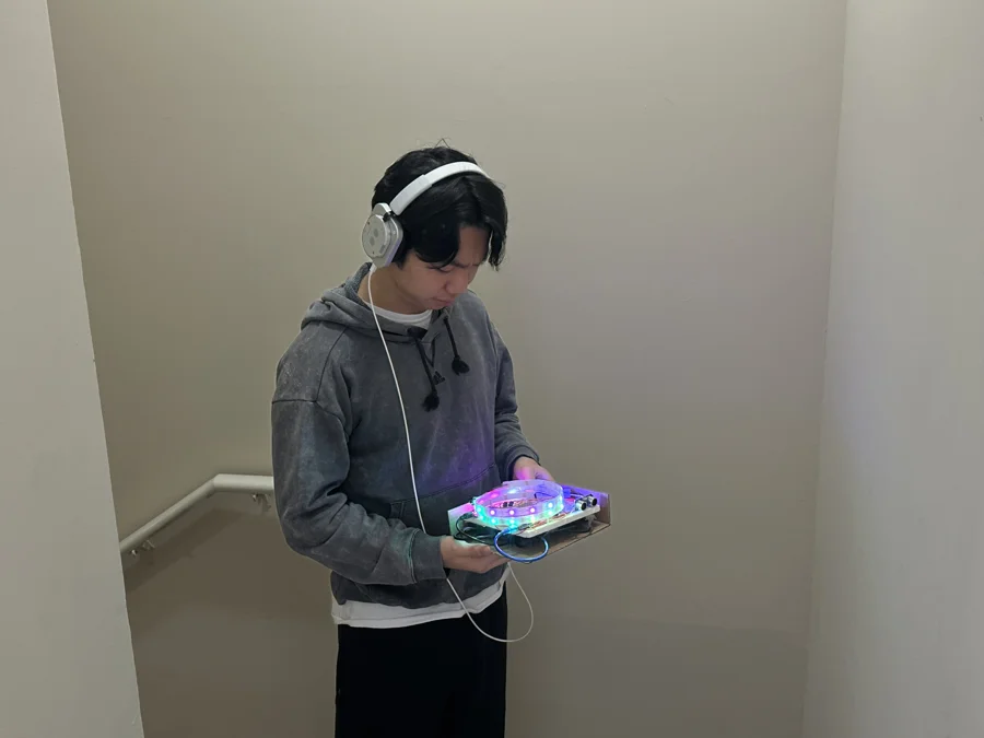 A person in headphones holds the glowing handheld station in a stairwell.